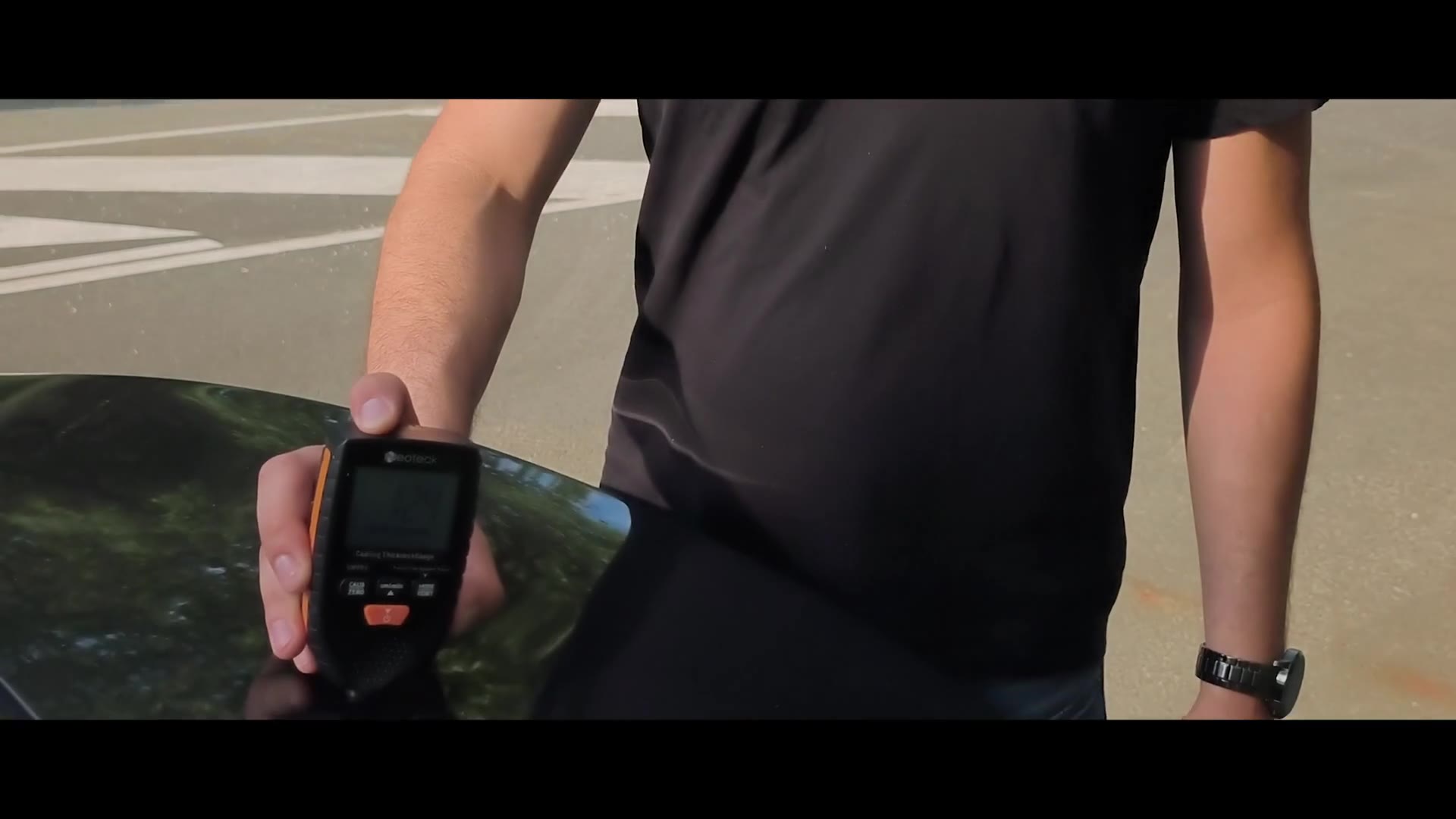 Paint-thickness gauge on a body panel — reading in micrometres